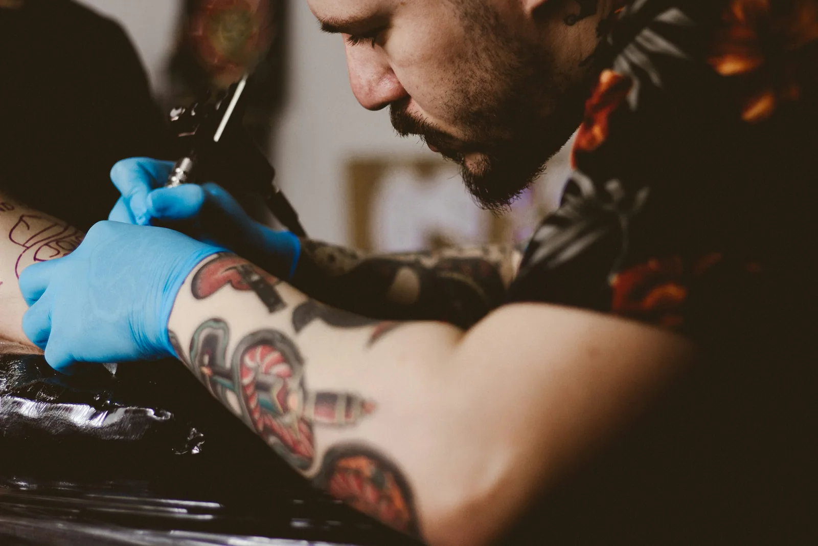 An InkSquad artist outlining a large arm tattoo on a client at the Phoenix shop