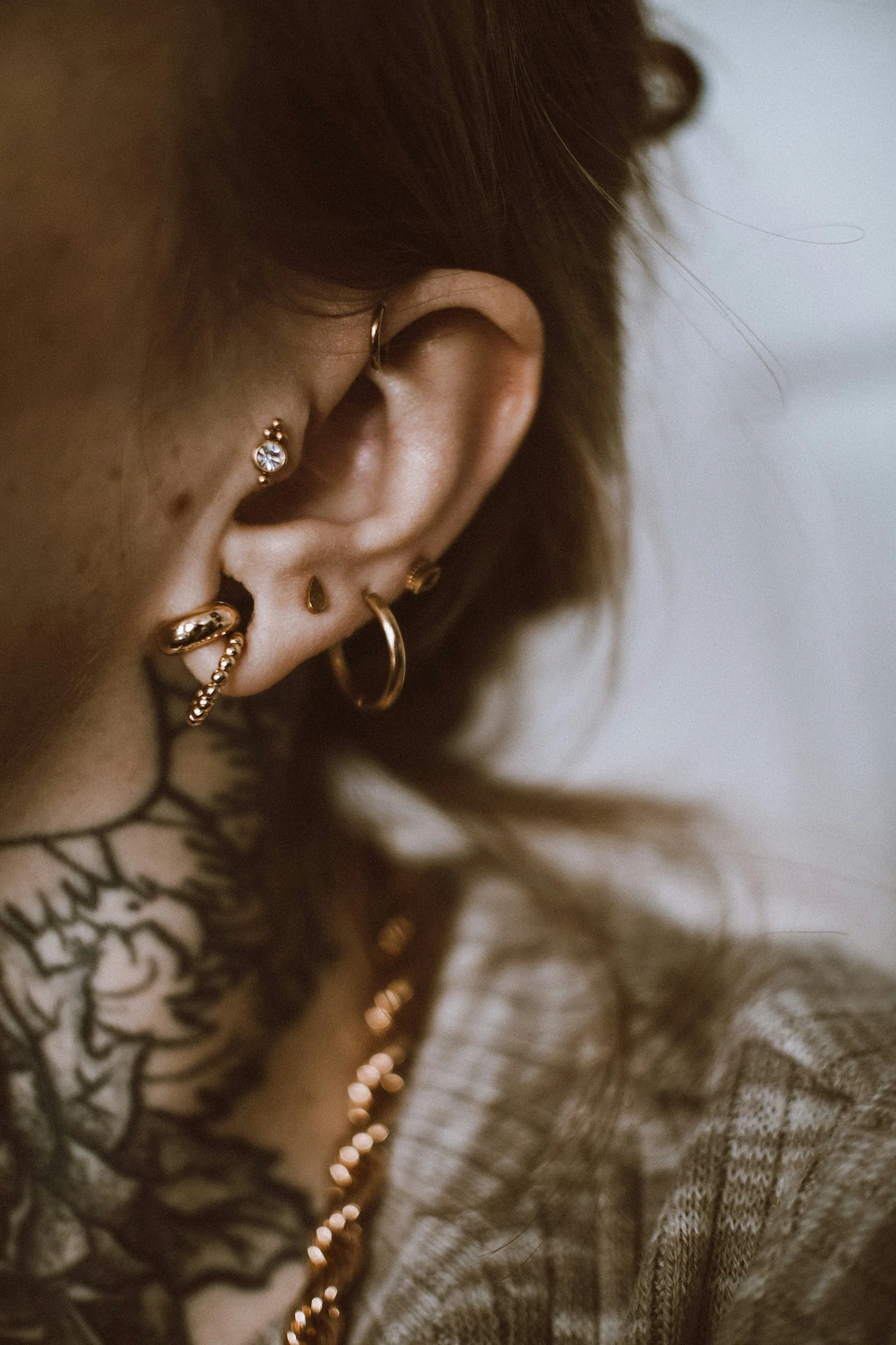 Stacked ear piercings including lobe and helix with gold hoops
