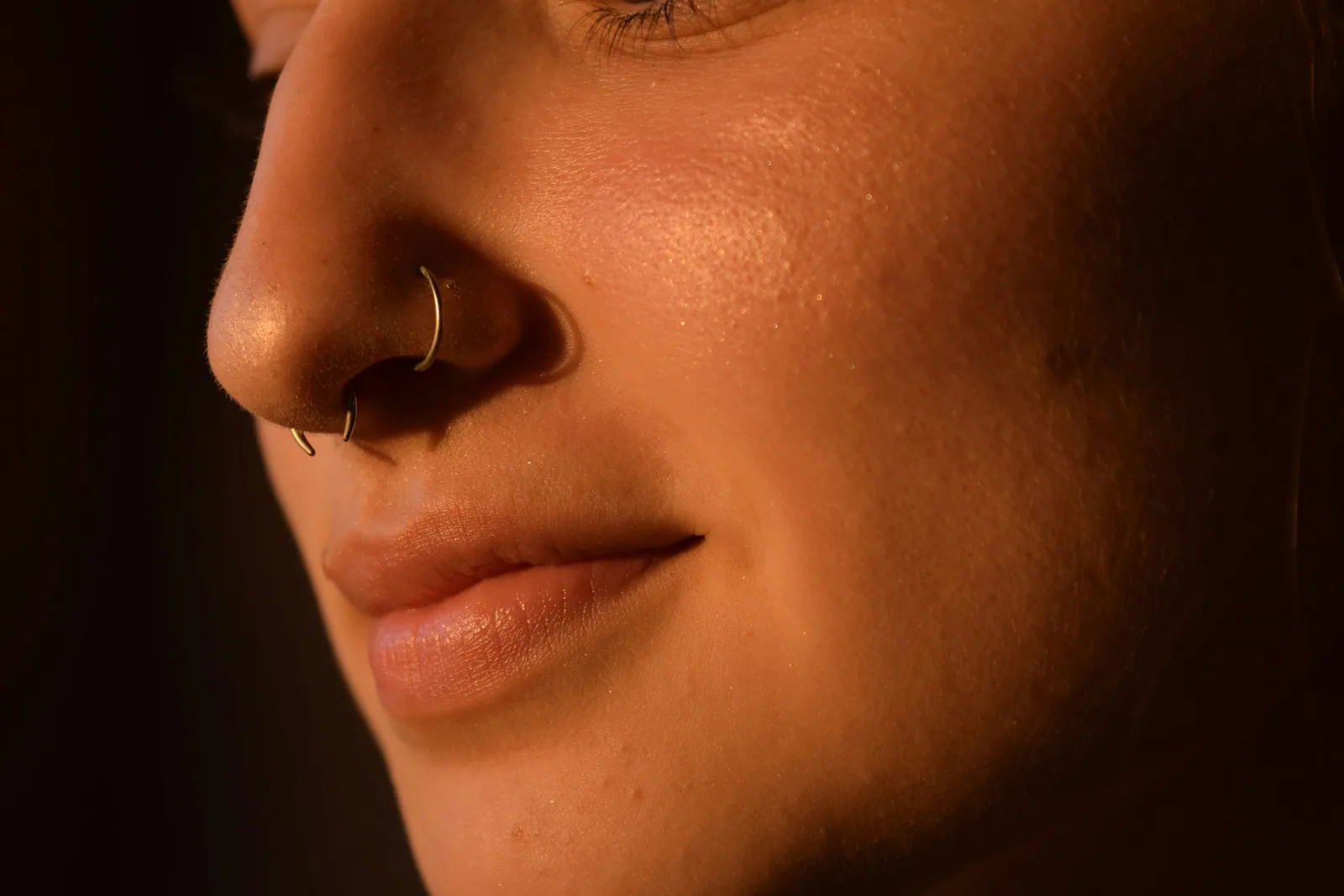 Close-up of a healed nostril piercing with a small gold stud