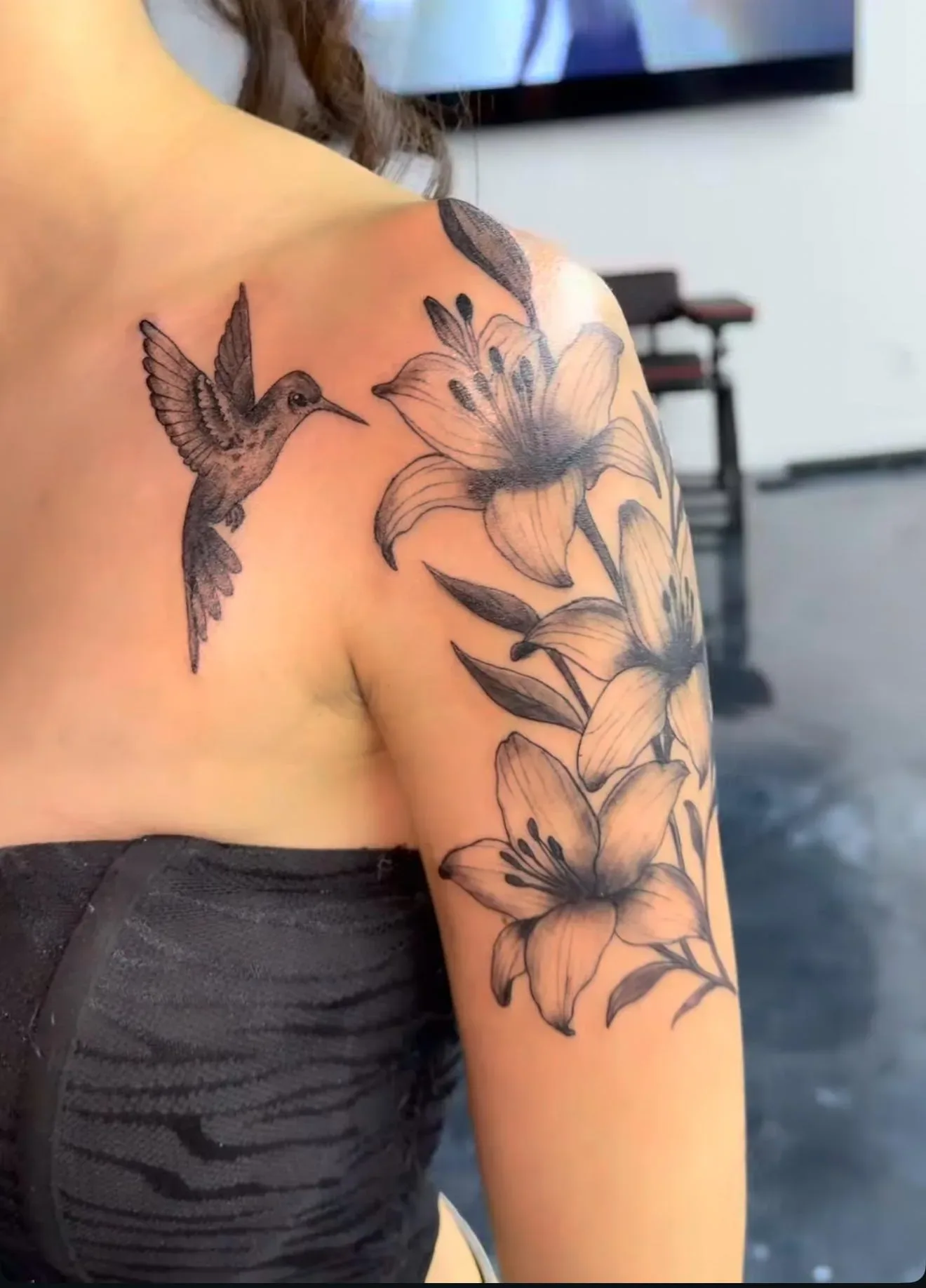 Fine line birds and flowers tattooed across a shoulder