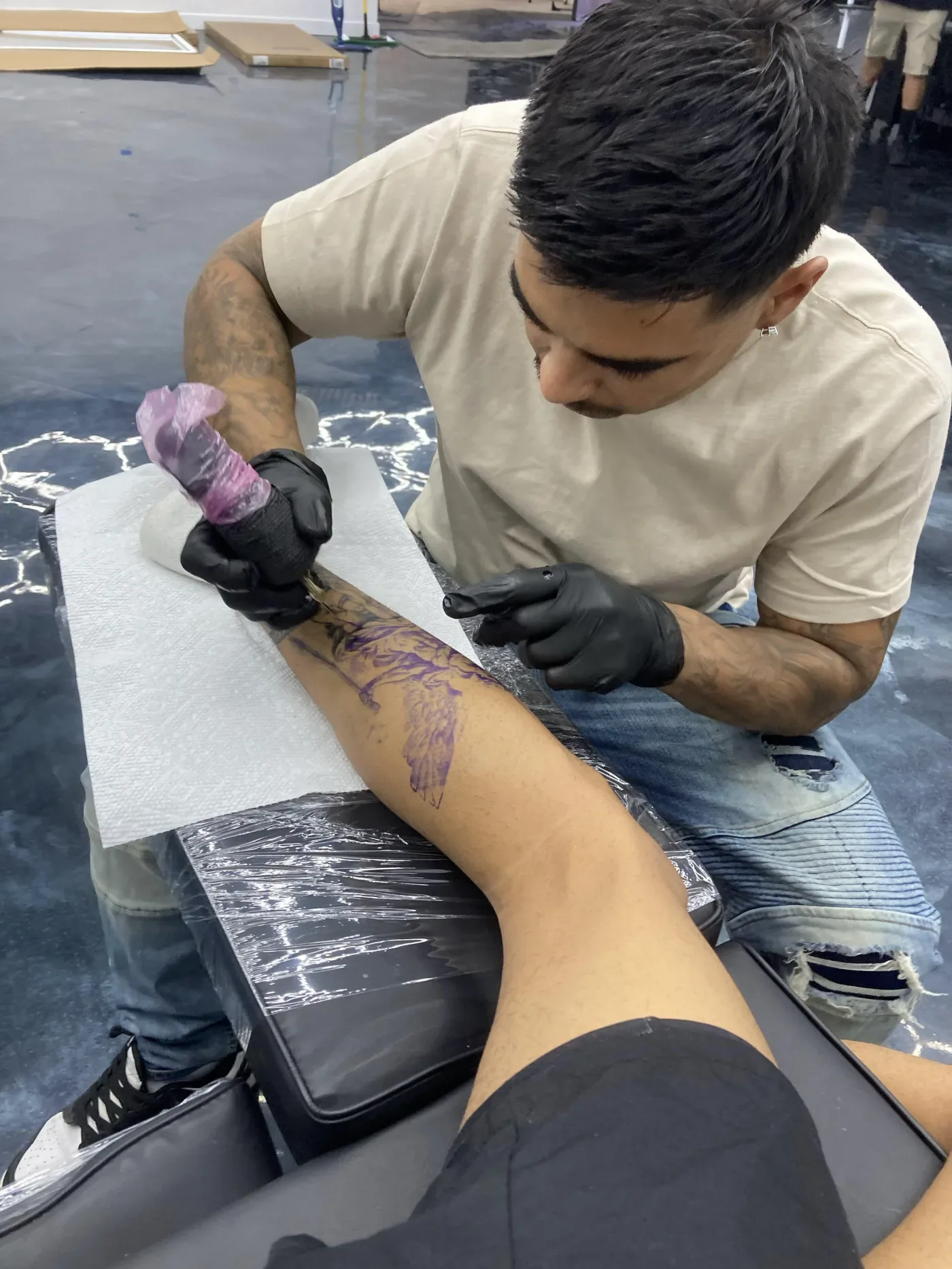 InkSquad artist tattooing a client's arm in the shop