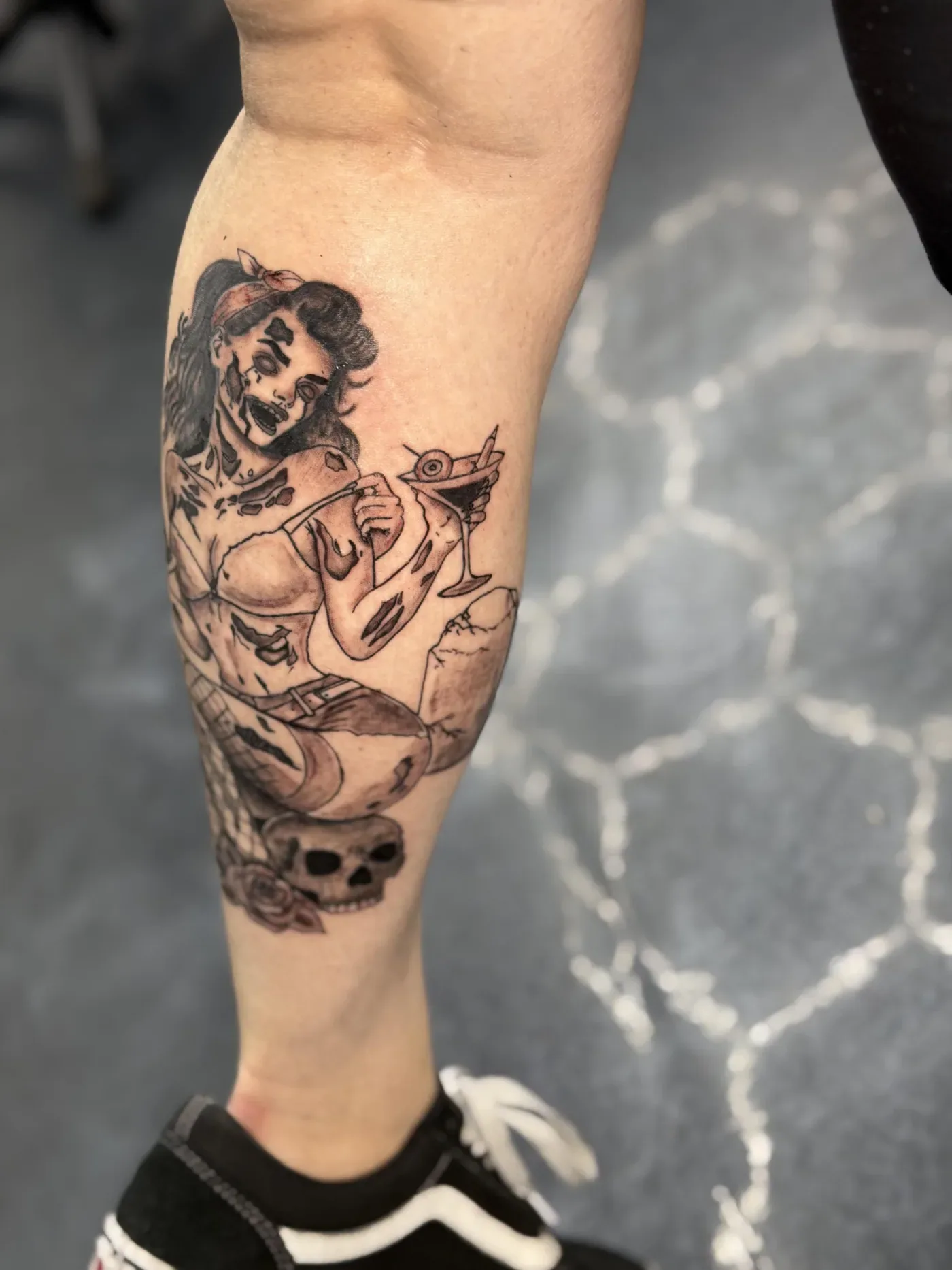 Black and gray calf tattoo of a figure and floral detail