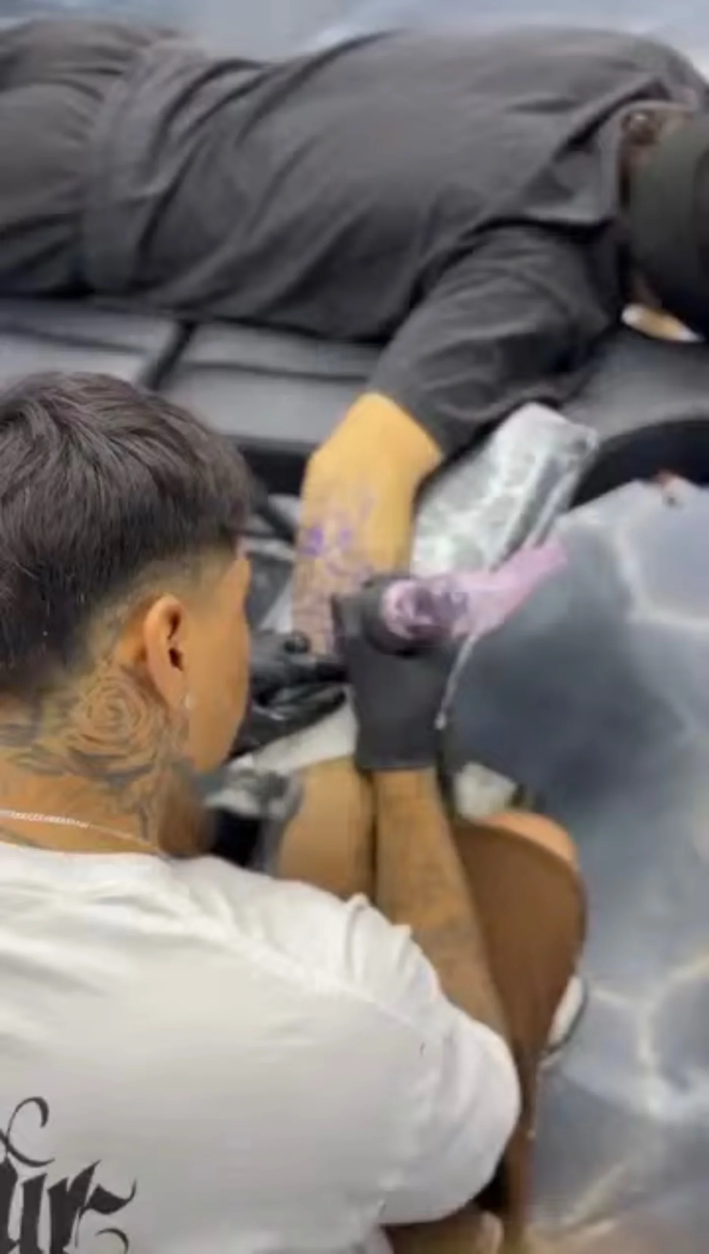 An InkSquad artist tattooing a client's leg at the Phoenix shop